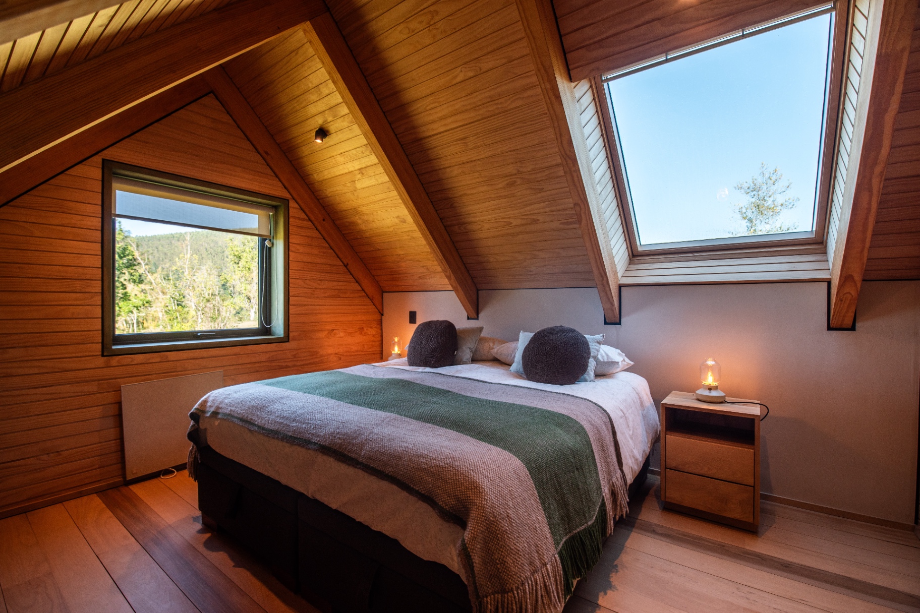 Dormitorio en altillo con lucarna y vista al bosque