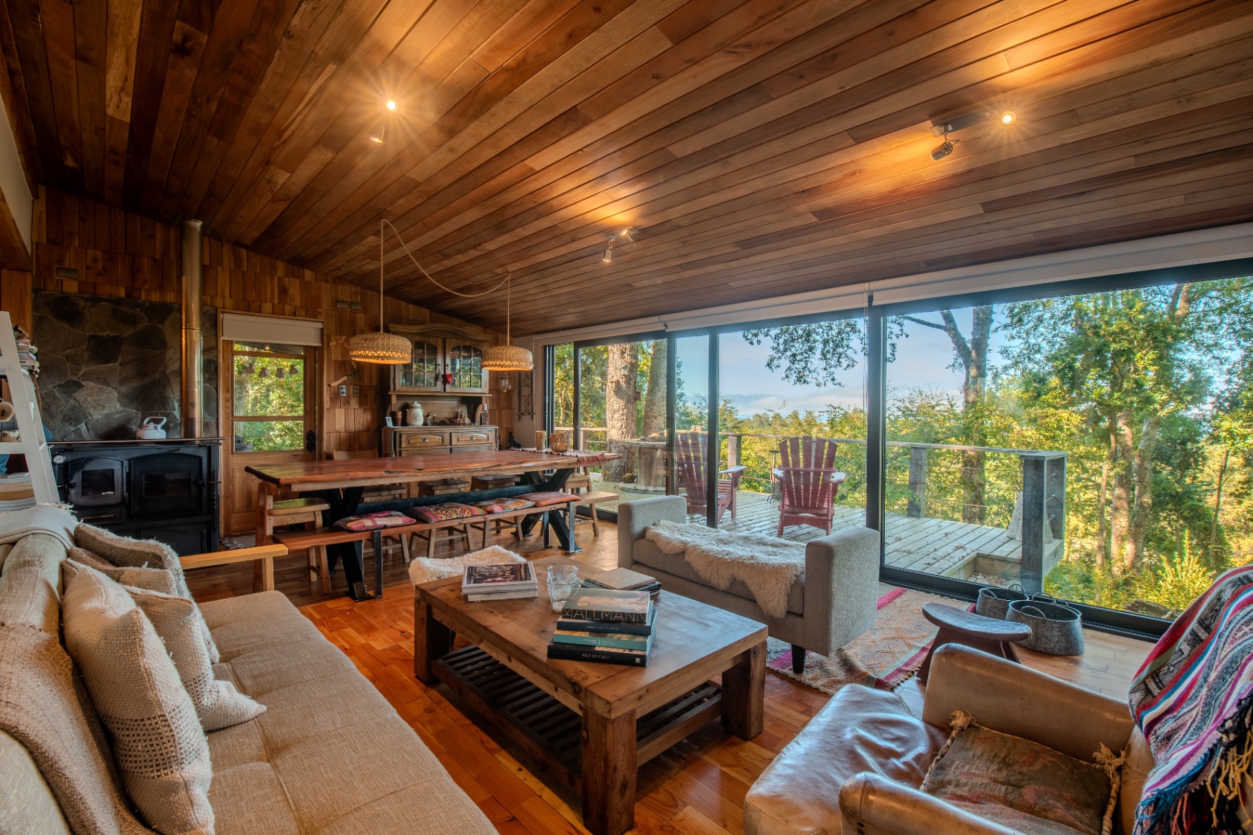 Interior de refugio en Fundo Leona con living y terraza hacia el bosque
